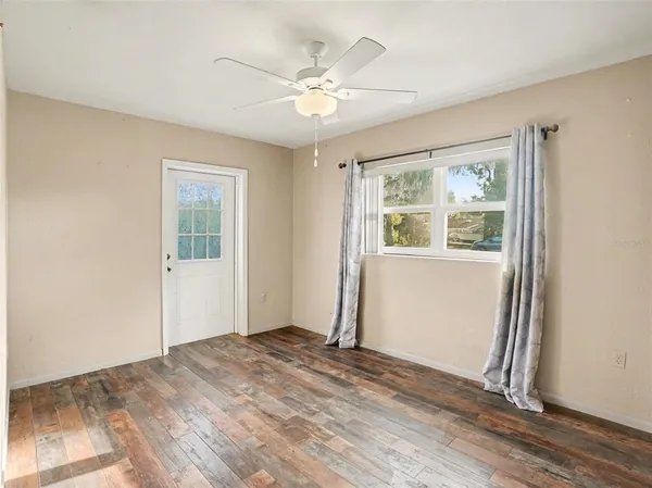 an empty room with wooden floor and windows