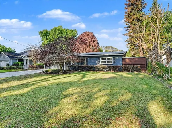 a view of a house with a big yard and large trees
