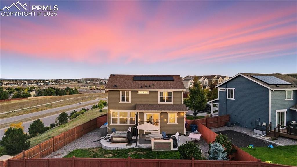10539 Casper Point Parker, CO 80134 - Photo 28 of 35 Back of property at dusk featuring an outdoor hangout area, a patio area, a fenced backyard, and roof mounted solar panels