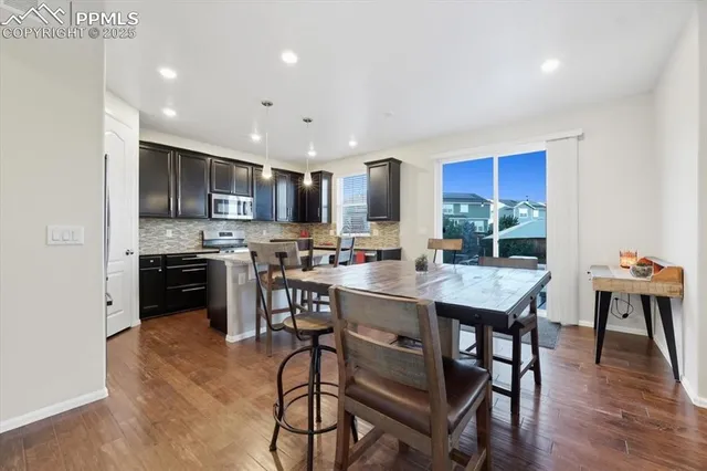 a kitchen with stainless steel appliances granite countertop a stove a sink a microwave a dining table and chairs