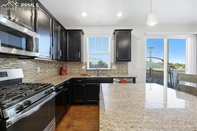 a kitchen with stainless steel appliances granite countertop a stove a sink and a microwave