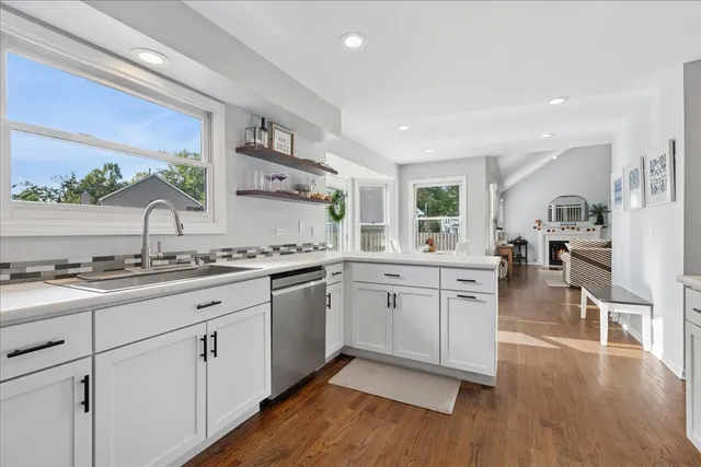 a open kitchen with granite countertop a stove top oven a sink a dining table and chairs