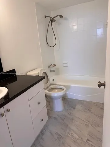 a bathroom with a granite countertop sink a toilet and shower
