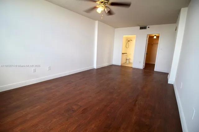 an empty room with wooden floor and chandelier fan