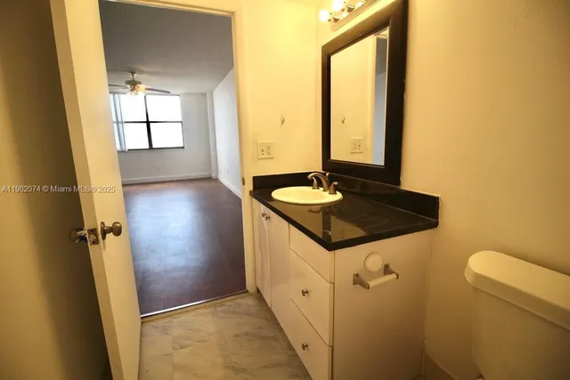 a bathroom with a granite countertop sink and a window