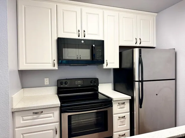a kitchen with appliances a refrigerator and cabinets