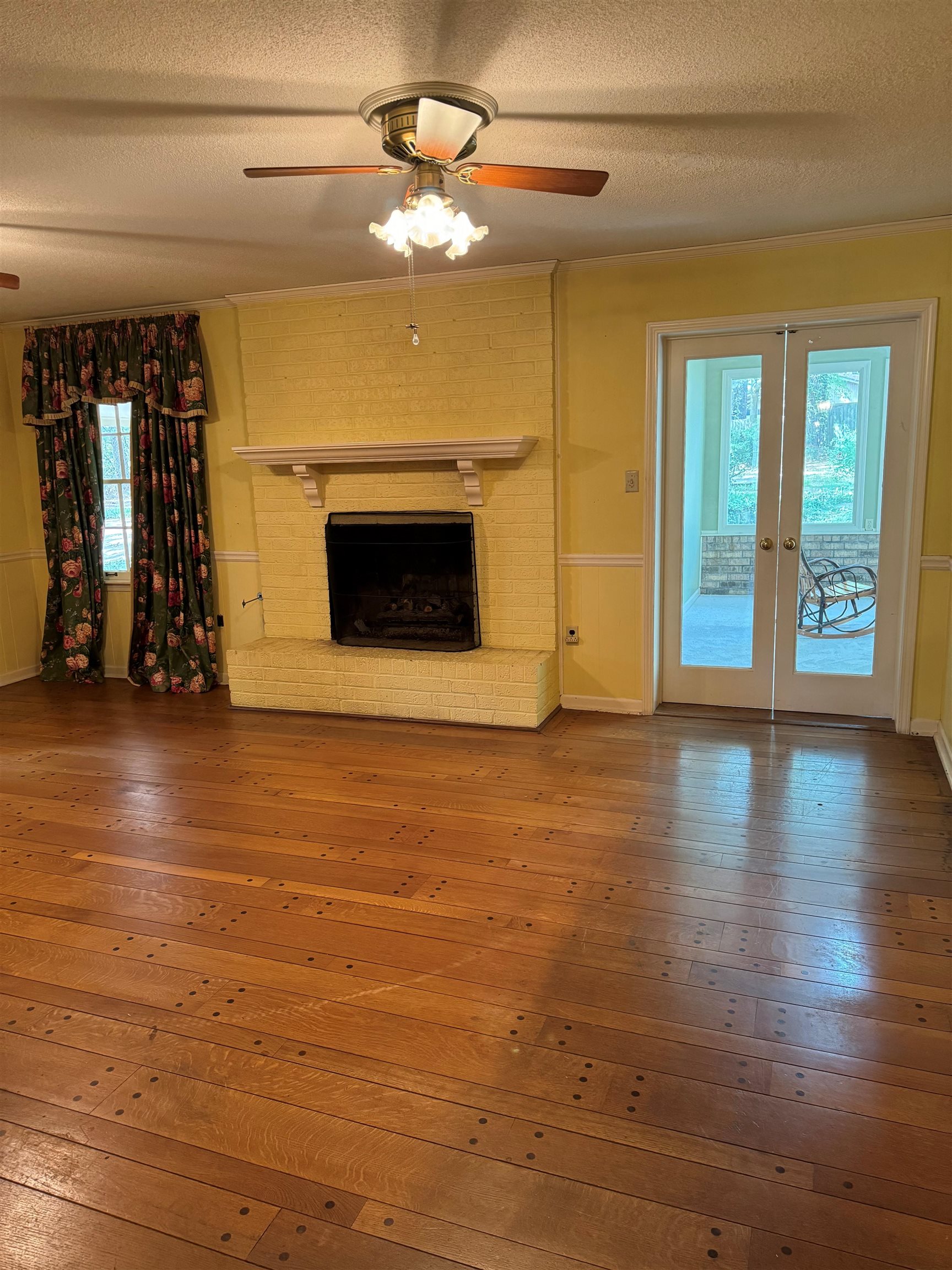 6738 River Birch Road Memphis, TN 38119 - Photo 8 of 17 Unfurnished living room featuring a textured ceiling, wood-type flooring, crown molding, a brick fireplace, and ceiling fan