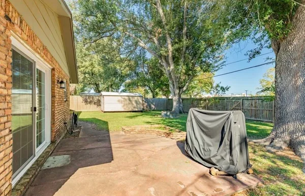 a view of a patio with table and chairs potted plants and large tree