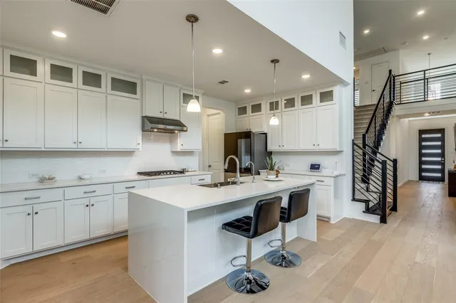 a kitchen with stainless steel appliances a sink a stove a refrigerator cabinets and a center island