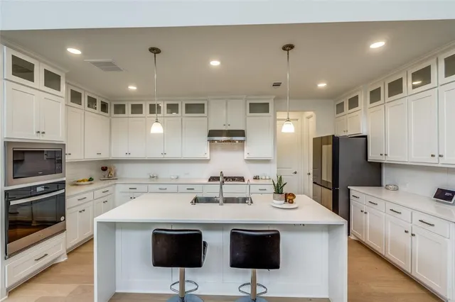 a kitchen with stainless steel appliances kitchen island granite countertop a sink refrigerator and cabinets
