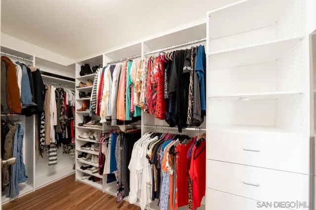 a view of walk in closet with clothes and shoes