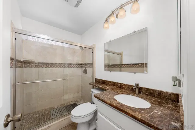 a bathroom with a granite countertop sink mirror vanity and toilet