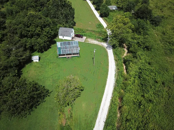 an aerial view of a house with a yard and trees all around