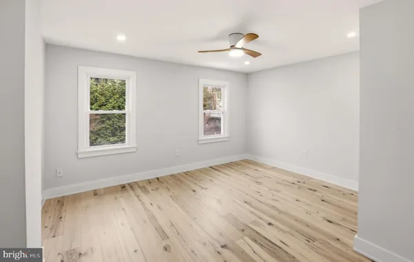 a view of empty room with wooden floor and fan