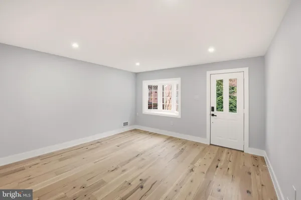 an empty room with wooden floor and windows