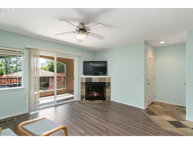 a view of an empty room with wooden floor fireplace and a window