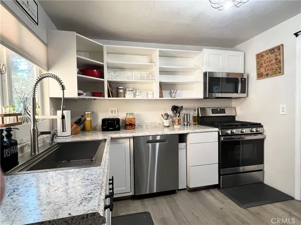 a kitchen with stainless steel appliances a stove a sink and white cabinets