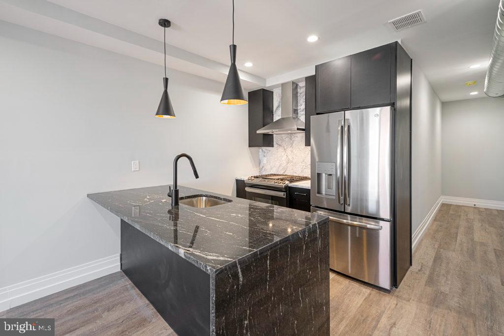 526 Brown Street, Unit 403 Philadelphia, PA 19123 - Photo 1 of 13 a kitchen with kitchen island a refrigerator a sink and wooden floor