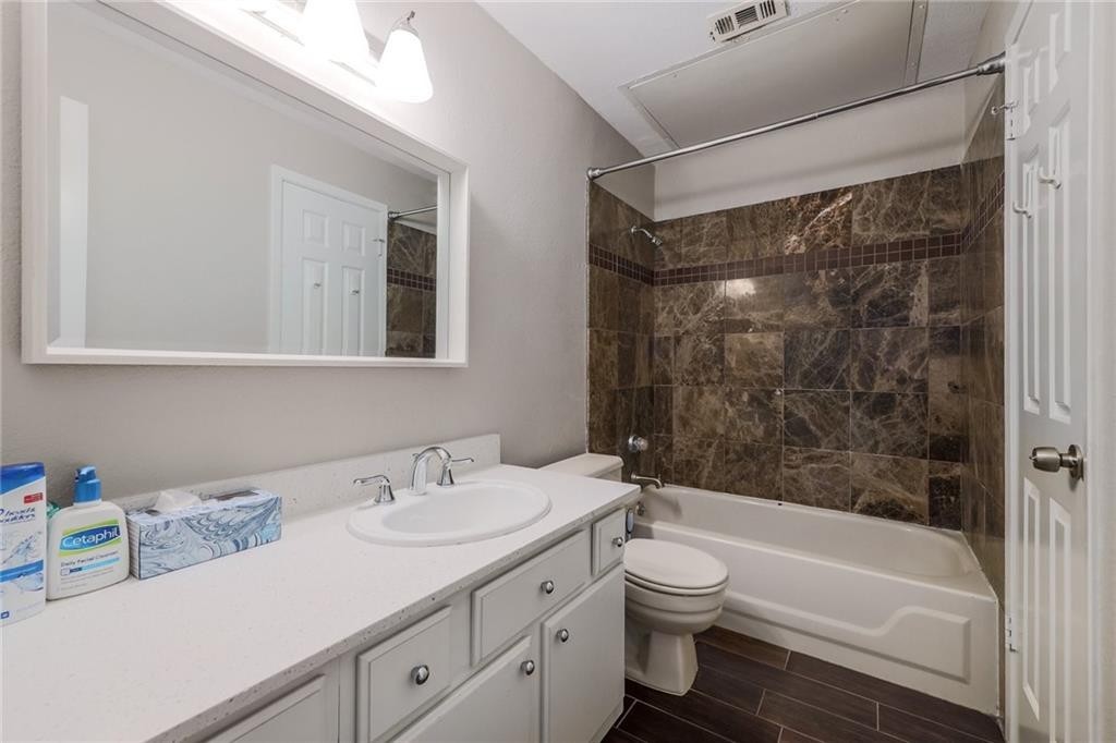 807 West 25th Street, Unit 206 Austin, TX 78705 - Photo 5 of 7 a bathroom with a granite countertop sink toilet a large mirror a bathtub and shower