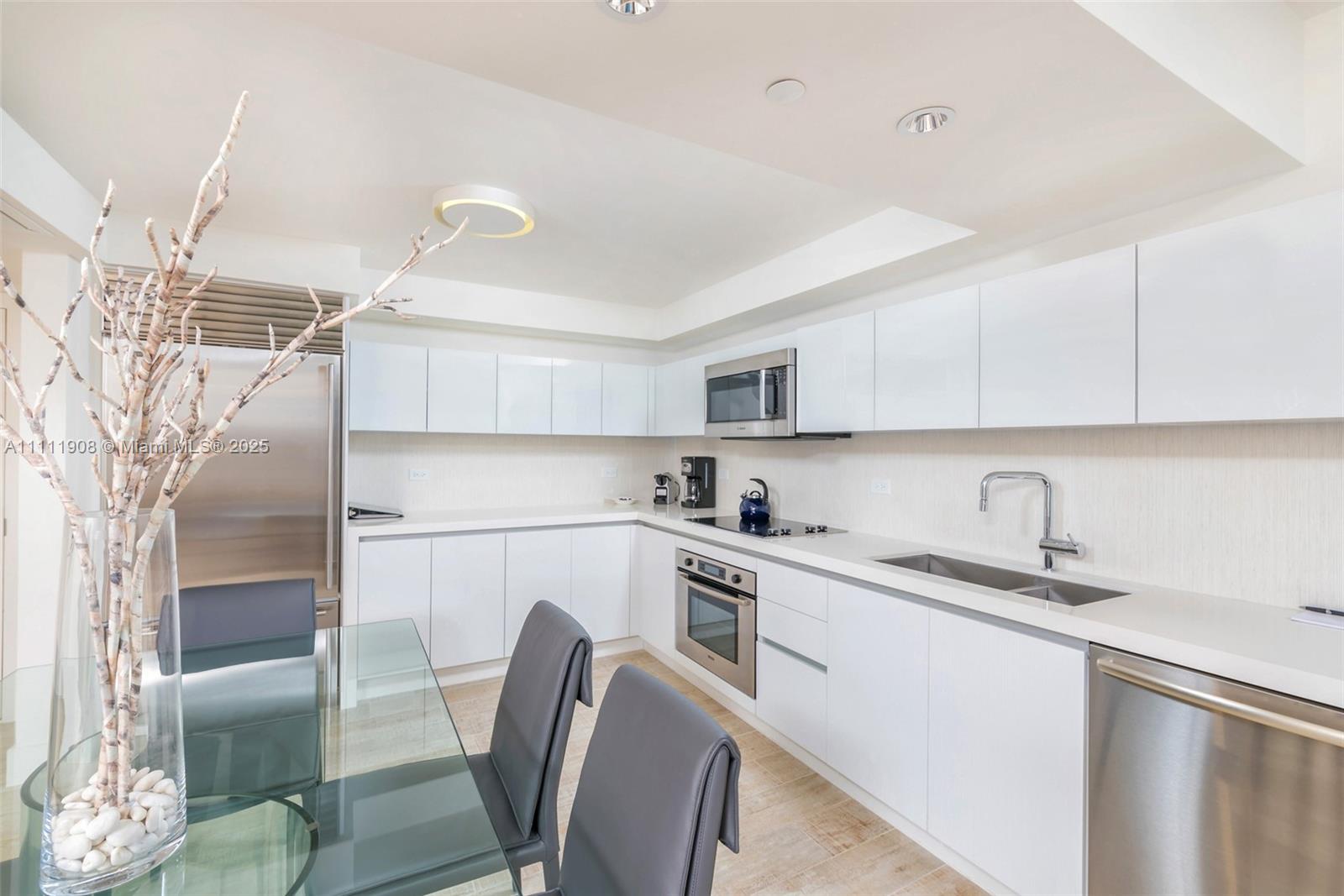 102 24th Street, Unit 1019 Miami Beach, FL 33139 - Photo 18 of 27 a kitchen with stainless steel appliances granite countertop a sink a stove a refrigerator with white cabinets and wooden floor