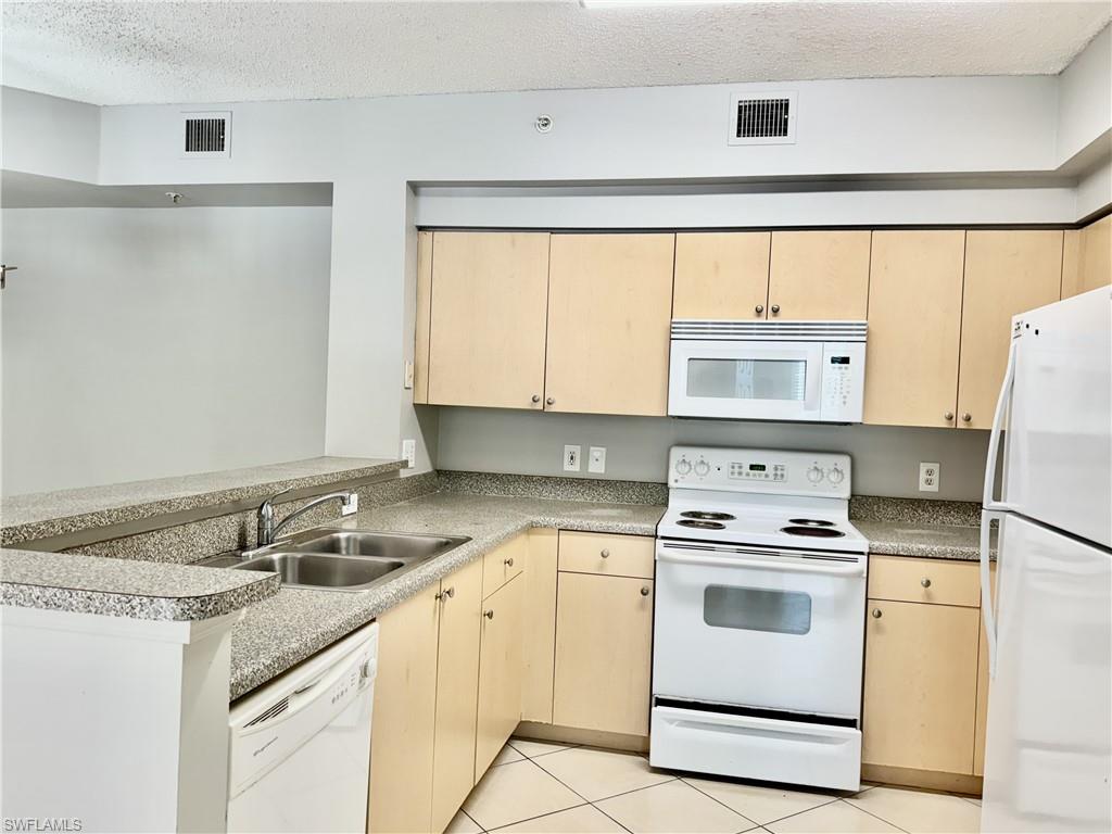 1200 Reserve Way, Unit 103 Naples, FL 34105 - Photo 17 of 26 a kitchen with granite countertop white cabinets and white appliances