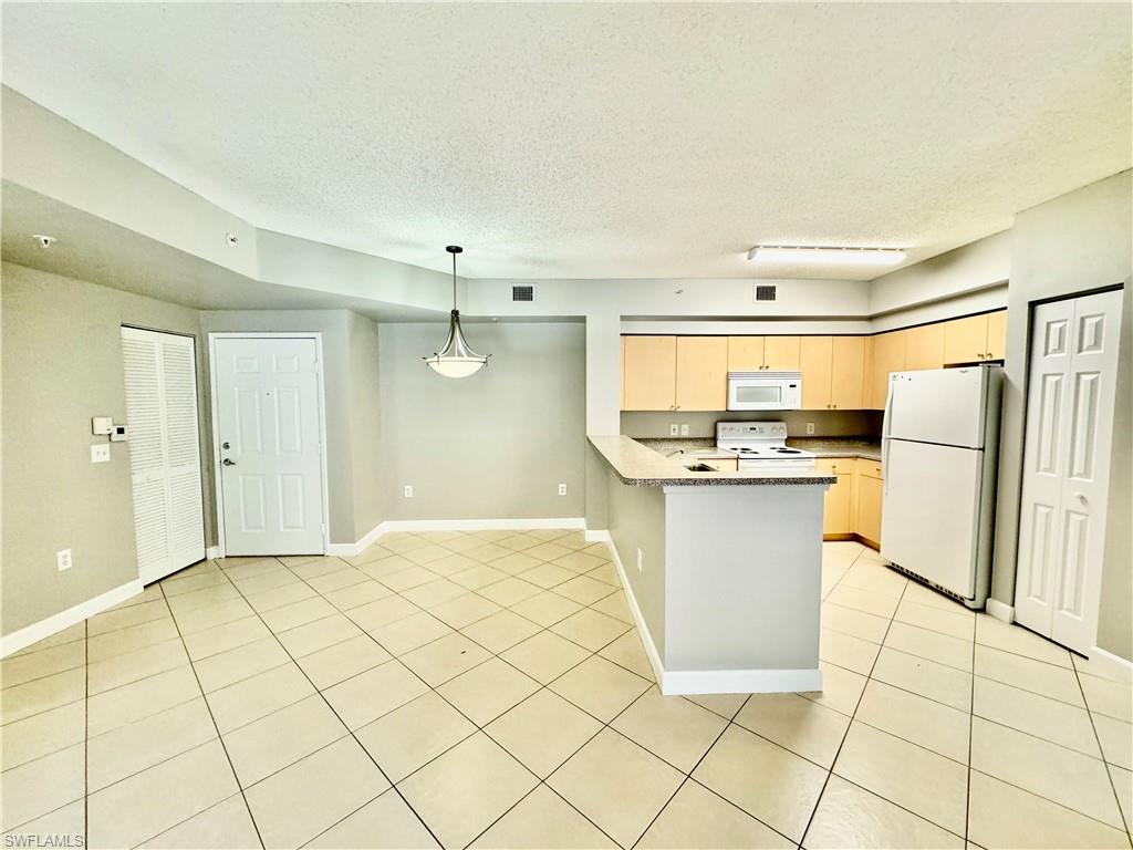 1200 Reserve Way, Unit 103 Naples, FL 34105 - Photo 5 of 26 a view of a kitchen with white cabinets and refrigerator