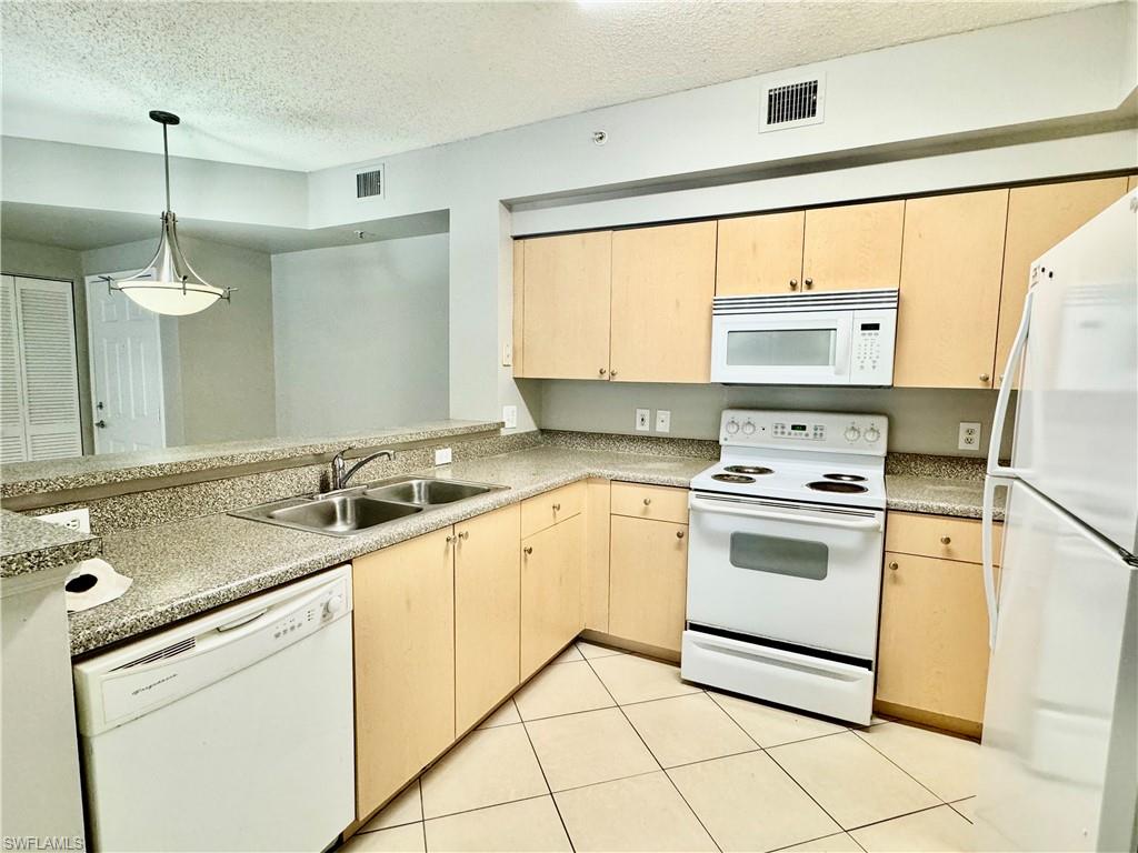1200 Reserve Way, Unit 103 Naples, FL 34105 - Photo 7 of 26 a kitchen with a sink stove and white cabinets