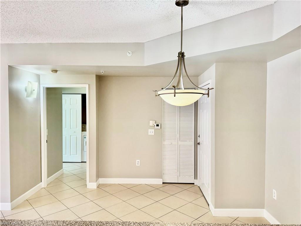 1200 Reserve Way, Unit 103 Naples, FL 34105 - Photo 8 of 26 a view of a hallway with a chandelier fan and windows
