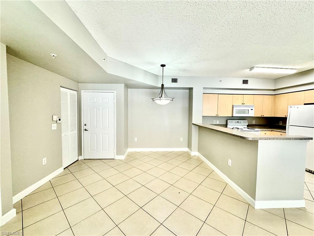 1200 Reserve Way, Unit 103 Naples, FL 34105 - Photo 9 of 26 a view of a kitchen with kitchen island granite countertop a refrigerator and a stove top oven