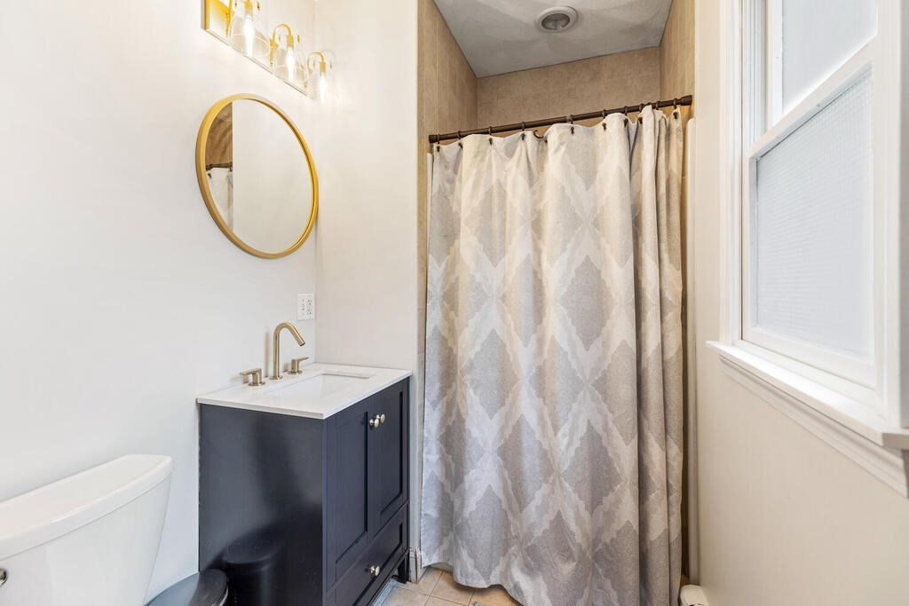 45 Spring Street Stoneham, MA 02180 - Photo 17 of 30 a bathroom with a sink a mirror and a shower curtain