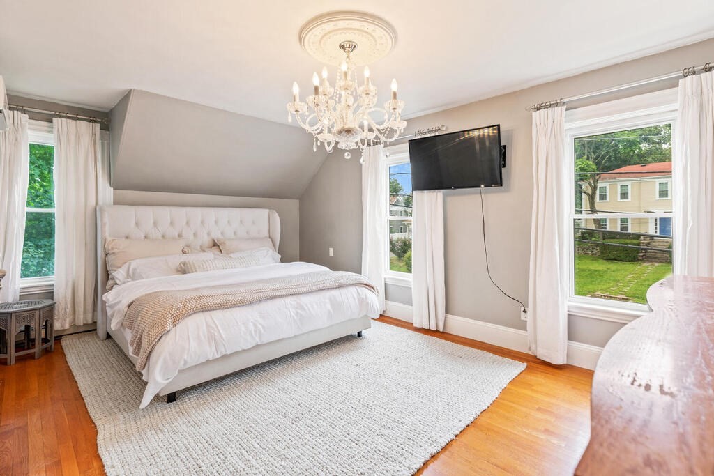 45 Spring Street Stoneham, MA 02180 - Photo 18 of 30 a spacious bedroom with a bed and a chandelier