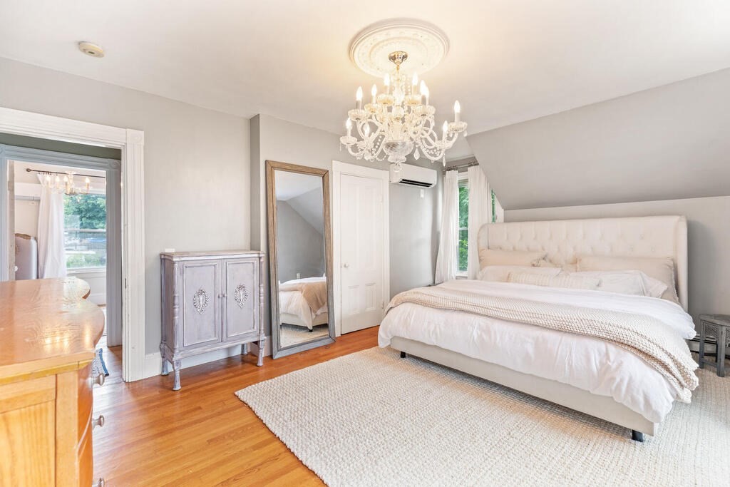 45 Spring Street Stoneham, MA 02180 - Photo 19 of 30 a spacious bedroom with a bed and a chandelier