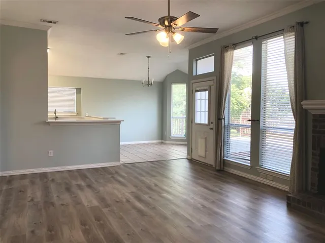 a view of an empty room with window and wooden floor