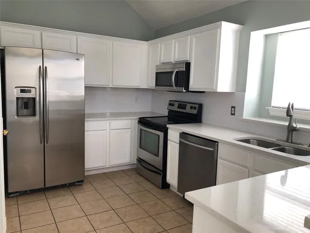 a kitchen with stainless steel appliances granite countertop a sink a stove a microwave and a refrigerator