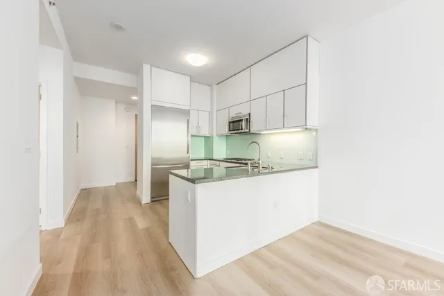 a kitchen with kitchen island a sink a stove a refrigerator and white cabinets