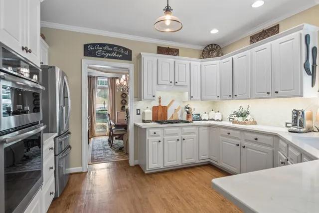 a kitchen with stainless steel appliances a dining table chairs and wooden floor