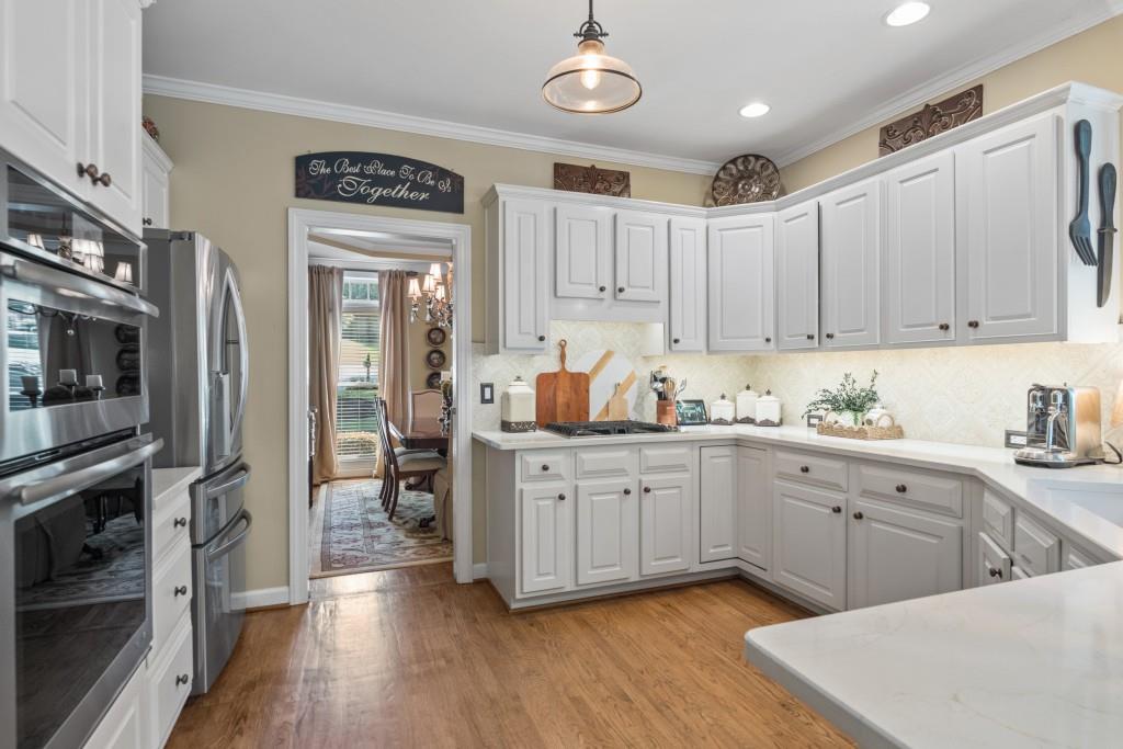4140 River Bluff Run Way Suwanee, GA 30024 - Photo 7 of 83 a kitchen with stainless steel appliances granite countertop a refrigerator oven a sink dishwasher and white cabinets with wooden floor