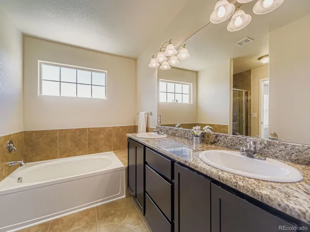 a bathroom with a granite countertop bathtub a sink and mirror