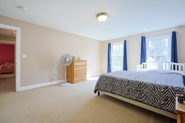 a bed sitting in a spacious bedroom next to a window and dresser