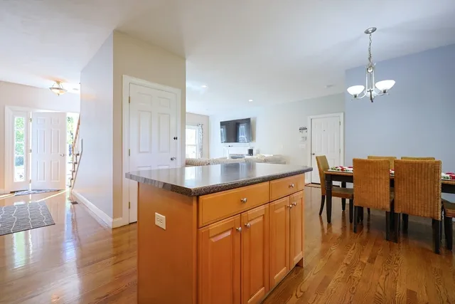 a kitchen with stainless steel appliances granite countertop a sink dishwasher a stove and a dining table with wooden floor