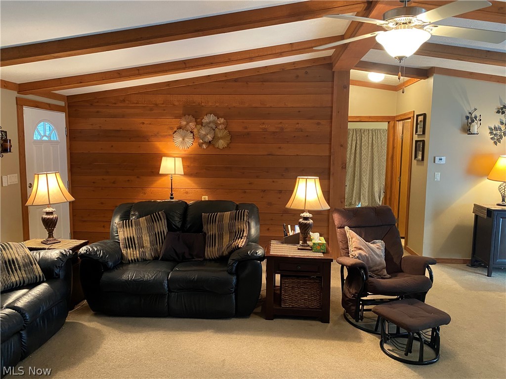 14980 Sprucevale Road East Liverpool, OH 43920 - Photo 10 of 19 Carpeted living room featuring vaulted ceiling with beams, ceiling fan, and wood walls