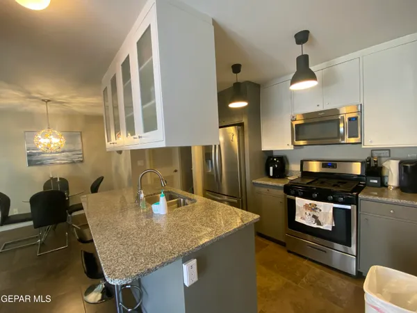 a kitchen with stainless steel appliances granite countertop a sink a stove and refrigerator