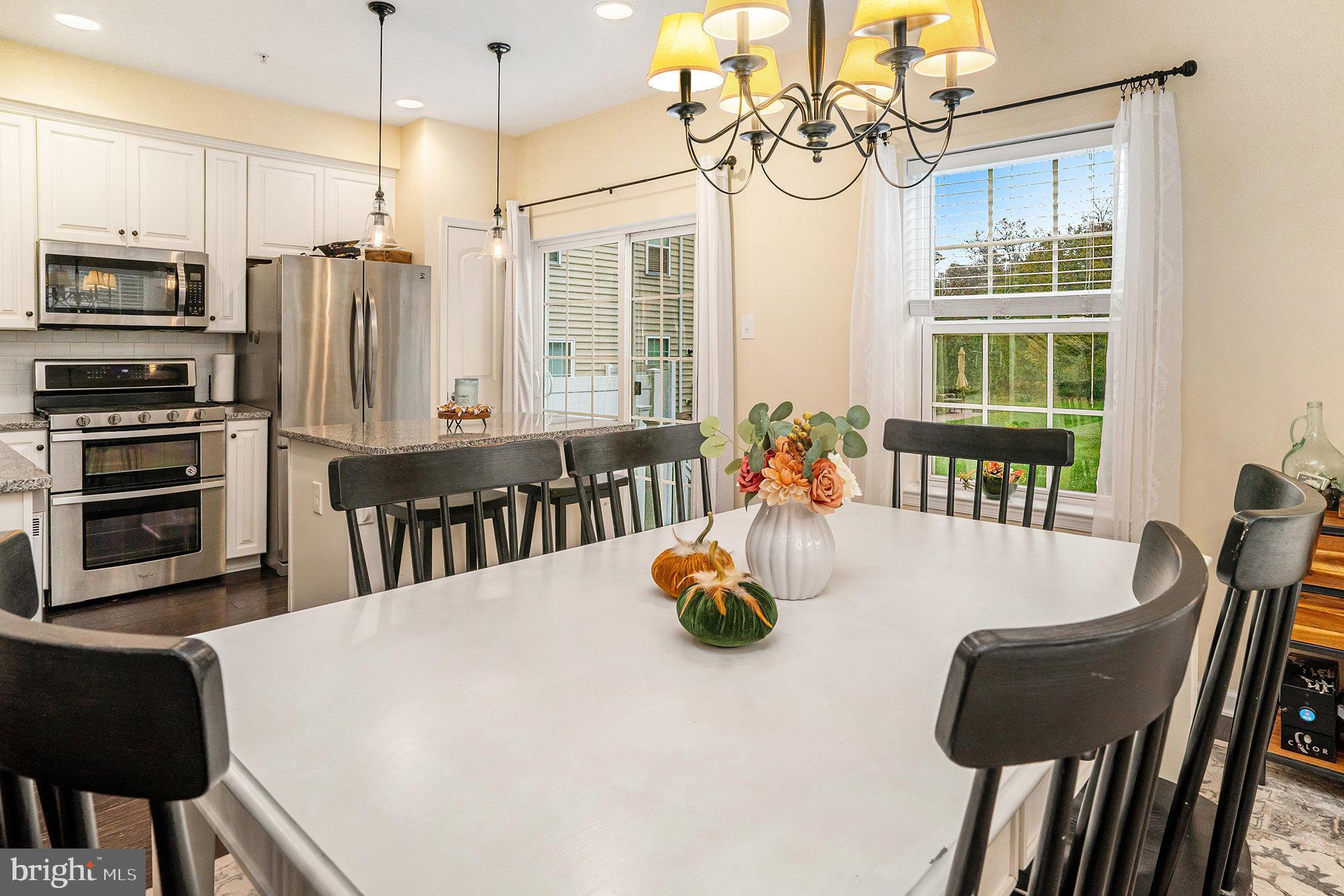 3611 Jacob Stout Road, Unit 8 Doylestown, PA 18902 - Photo 10 of 39 a kitchen with stainless steel appliances kitchen island granite countertop a table chairs in it and wooden floors