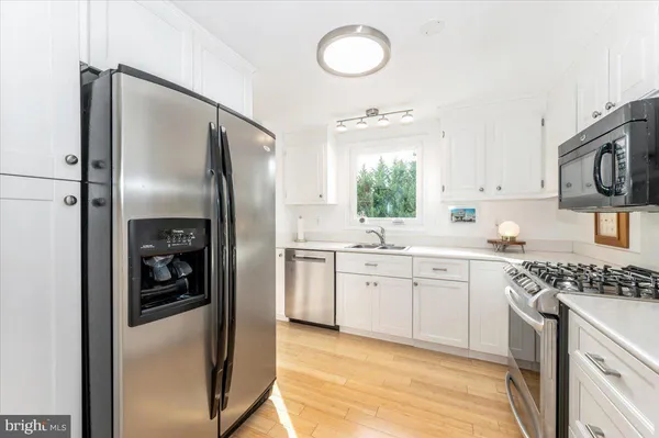 a kitchen with stainless steel appliances granite countertop a sink stove a oven and white cabinets with wooden floor