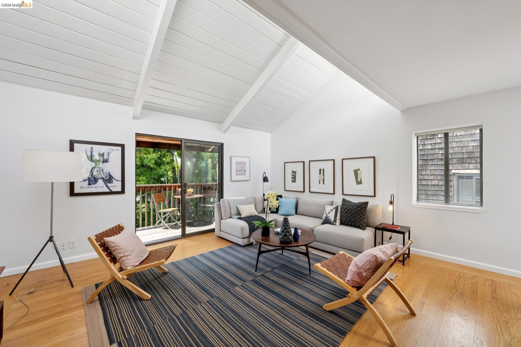 1340 Henry Street Berkeley, CA 94709 - Photo 6 of 52 Living area featuring wood-finish flooring, a vaulted ceiling with exposed beams, a glass sliding door opening to a private balcony, a large window, and recessed lighting