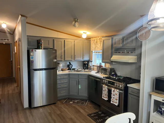 a kitchen with stainless steel appliances a refrigerator a sink and wooden floors