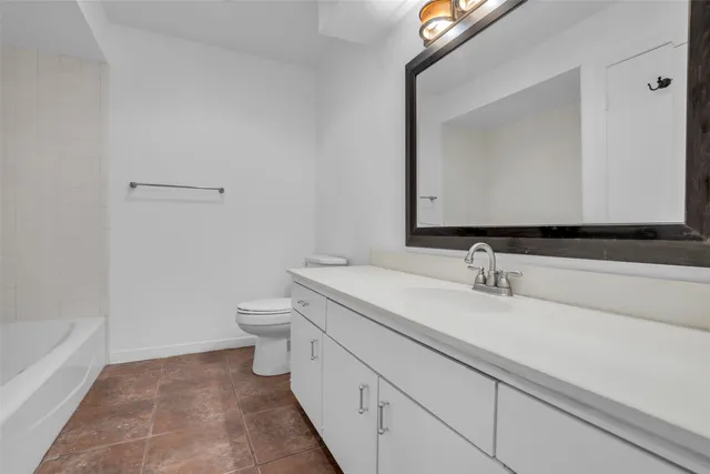 a bathroom with a granite countertop sink a toilet and a mirror