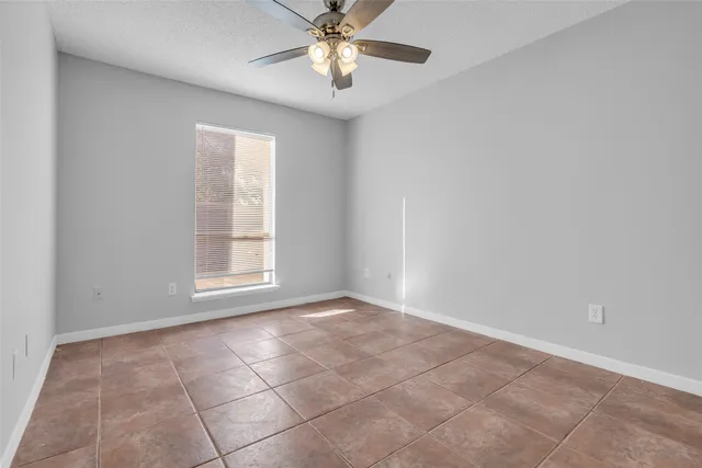 an empty room with chandelier fan and windows