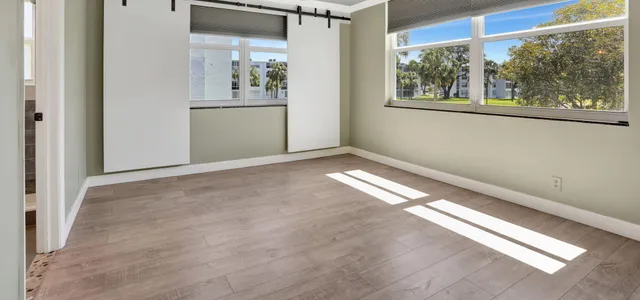 a view of a big room with wooden floor and windows