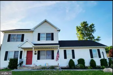 a view of a white house with large windows and a yard with plants